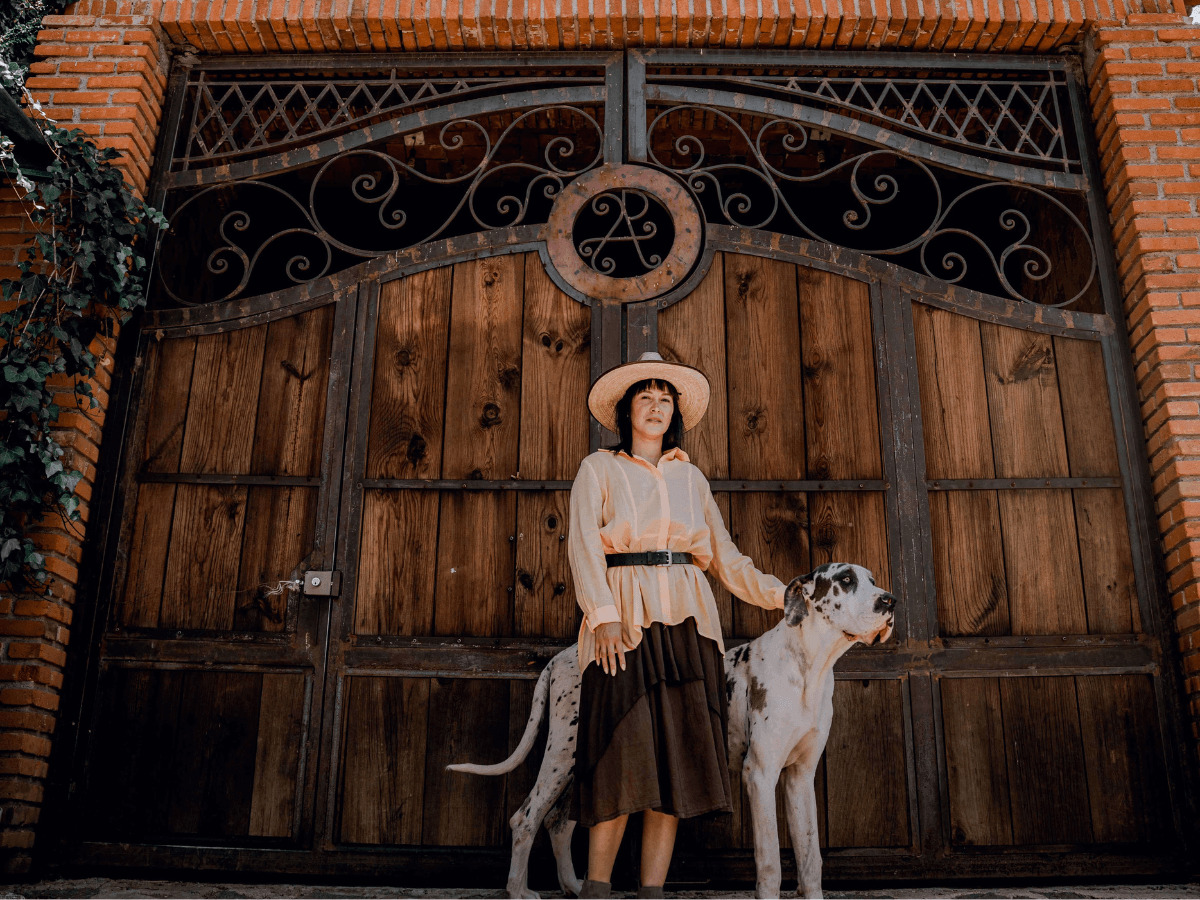門の前に立つ女性と犬